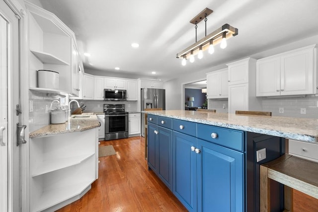 kitchen featuring a sink, open shelves, blue cabinetry, white cabinets, and appliances with stainless steel finishes