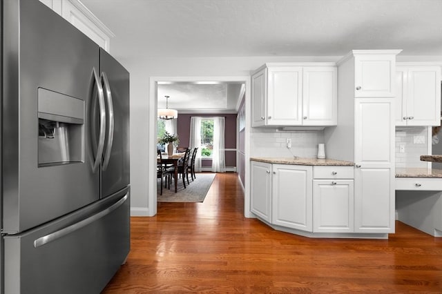 kitchen with decorative backsplash, wood finished floors, stainless steel fridge with ice dispenser, and white cabinets