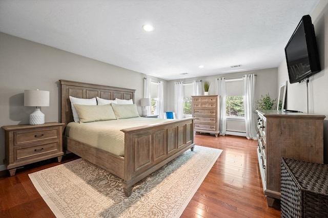bedroom with baseboard heating, dark wood finished floors, recessed lighting, and visible vents