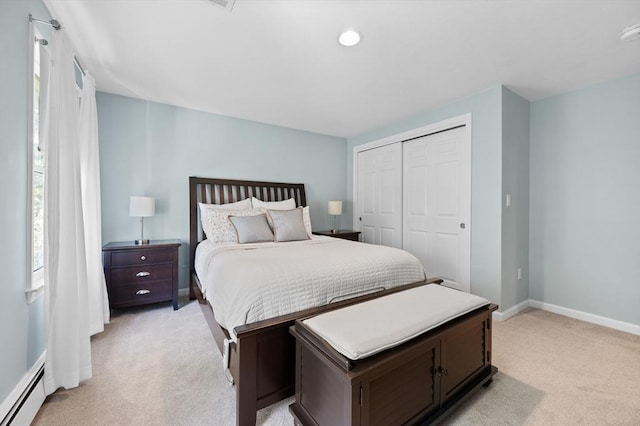 bedroom featuring light carpet, a closet, baseboards, and a baseboard heating unit