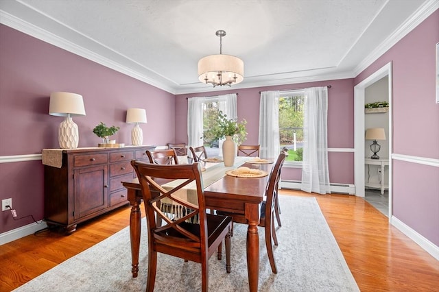 dining area with an inviting chandelier, light wood-style flooring, baseboards, a baseboard radiator, and ornamental molding