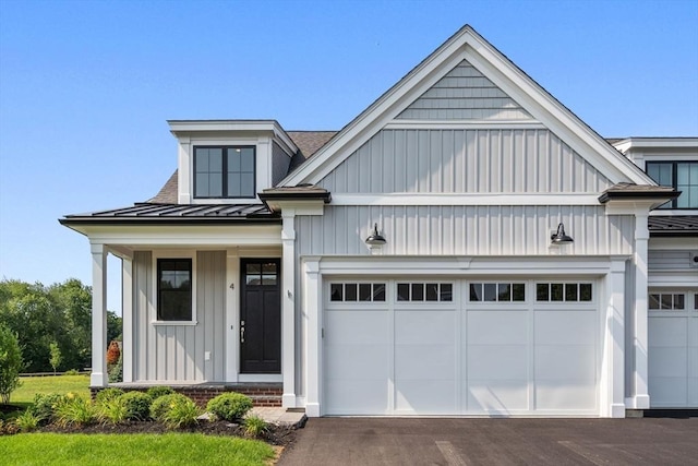 view of front facade with board and batten siding, driveway, a standing seam roof, metal roof, and an attached garage