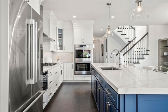 kitchen with recessed lighting, blue cabinets, a sink, appliances with stainless steel finishes, and dark wood-style floors