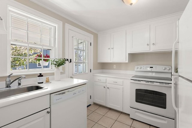 kitchen with a sink, light tile patterned floors, a healthy amount of sunlight, and white appliances