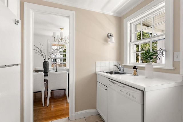 bar featuring a sink, ornamental molding, white appliances, and a healthy amount of sunlight