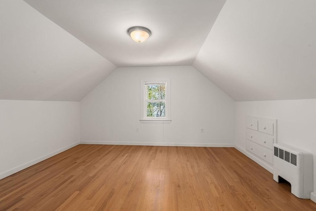 bonus room featuring radiator heating unit, baseboards, vaulted ceiling, and light wood-type flooring