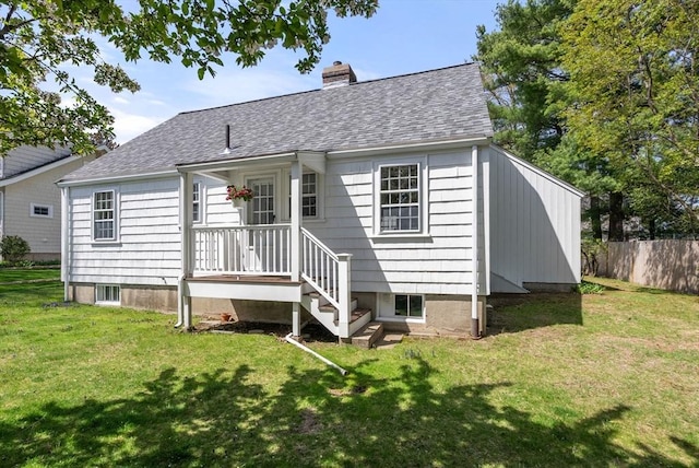 back of property featuring roof with shingles, fence, a yard, and a chimney