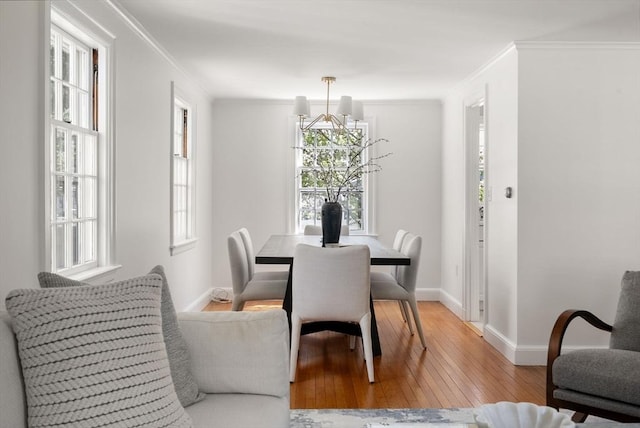 dining area with baseboards, light wood-style flooring, and crown molding