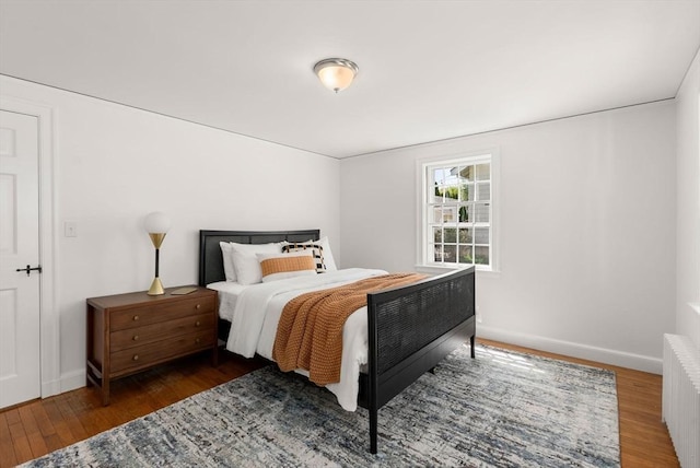 bedroom featuring wood finished floors, baseboards, and radiator heating unit