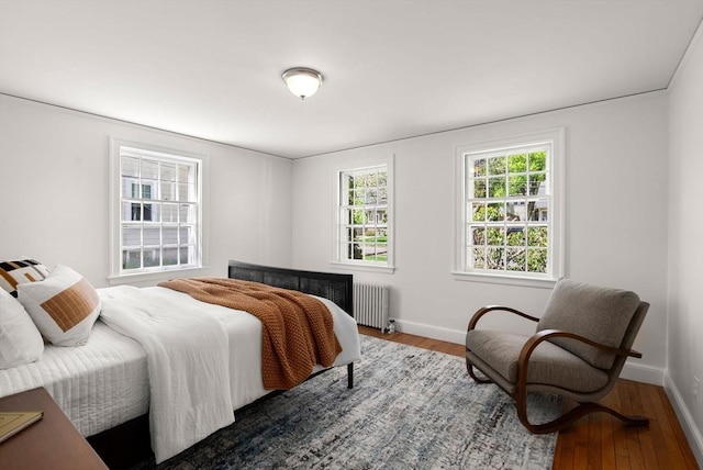 bedroom featuring baseboards, radiator, and wood finished floors