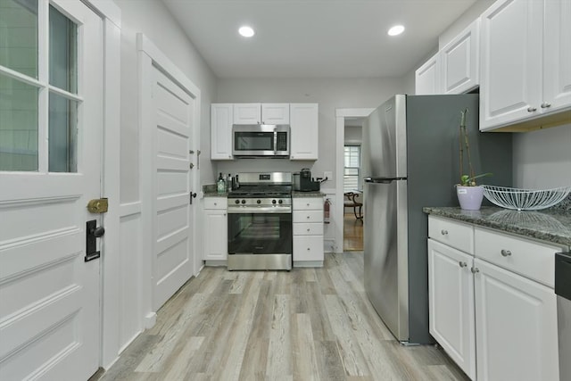 6 Brewer St Unit 2, Cambridge, MA 02138 - kitchen featuring appliances with stainless steel finishes, light wood-style floors, white cabinets, recessed lighting, and dark stone counters