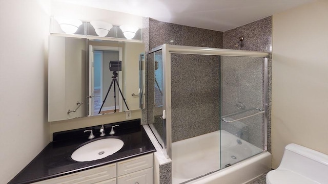 bathroom featuring toilet, combined bath / shower with glass door, and vanity