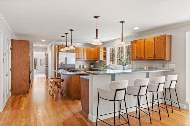kitchen with ornamental molding, backsplash, stainless steel appliances, and a peninsula