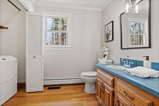 bathroom with vanity, ornamental molding, washer / dryer, wood finished floors, and a baseboard radiator