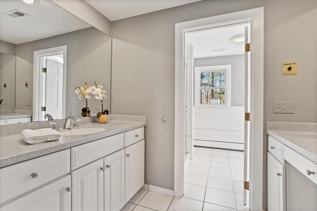 bathroom with visible vents, tile patterned flooring, vanity, baseboards, and a baseboard heating unit