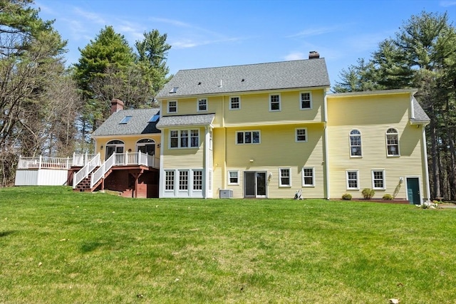 rear view of house with a lawn, stairs, a chimney, and a deck