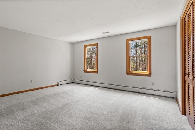 unfurnished room featuring carpet flooring, visible vents, a wealth of natural light, and a baseboard radiator