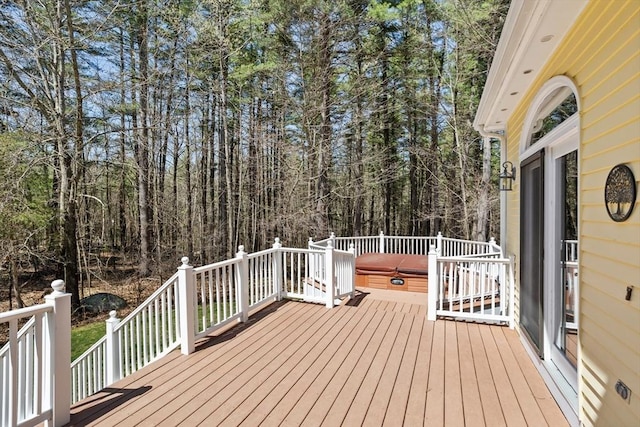 deck featuring a wooded view and a covered hot tub