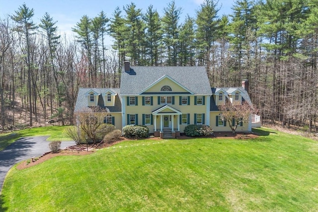 view of front of property featuring a shingled roof, a chimney, and a front yard
