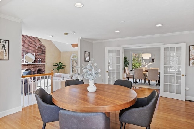 dining area featuring french doors, a fireplace, baseboards, light wood finished floors, and recessed lighting