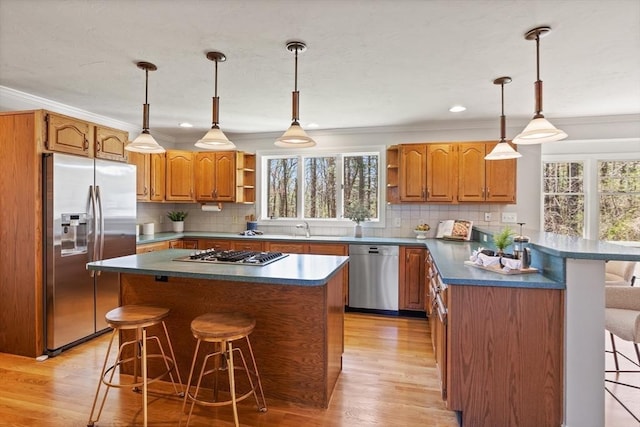 kitchen with a breakfast bar area, appliances with stainless steel finishes, open shelves, ornamental molding, and a wealth of natural light