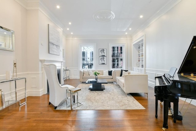 living area with a decorative wall, wood finished floors, a wainscoted wall, and ornamental molding