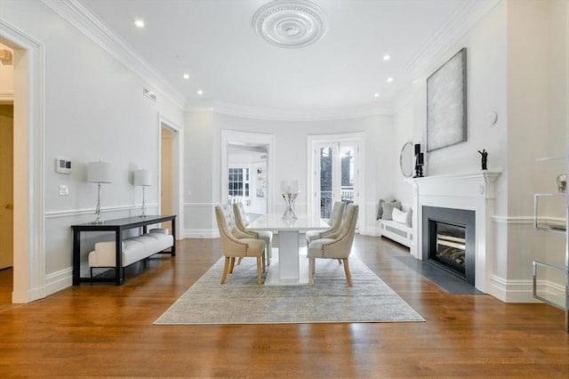 dining space featuring wood finished floors, baseboards, a fireplace with flush hearth, recessed lighting, and ornamental molding
