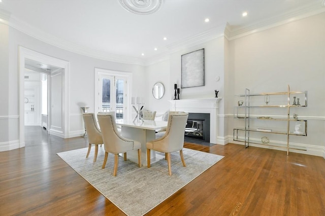 dining space featuring crown molding, wood finished floors, and baseboards