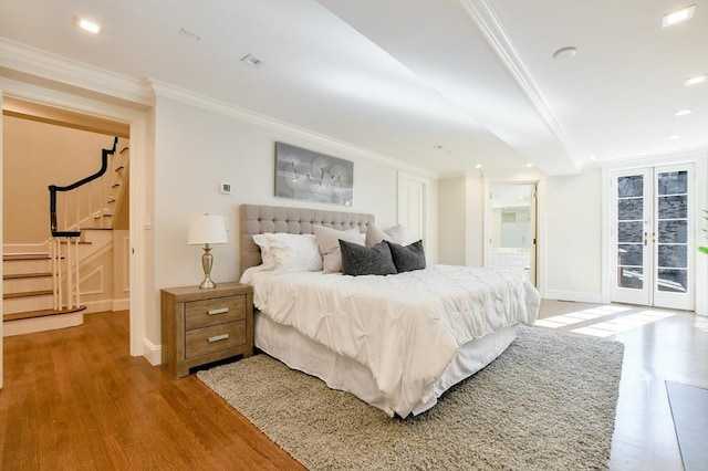 bedroom featuring wood finished floors, connected bathroom, french doors, crown molding, and access to exterior