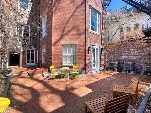 back of house with cooling unit, brick siding, and a patio area