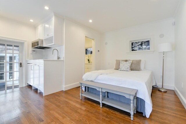 bedroom with ornamental molding, a sink, wood finished floors, recessed lighting, and baseboards
