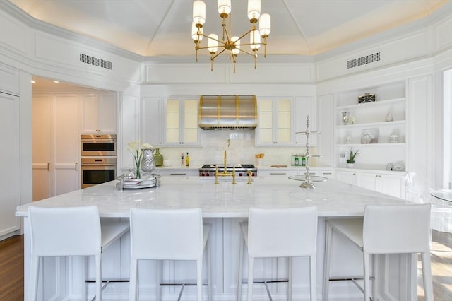 kitchen with visible vents, open shelves, white cabinetry, wall chimney exhaust hood, and a notable chandelier