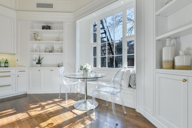 dining room featuring visible vents, plenty of natural light, built in shelves, and dark wood-type flooring