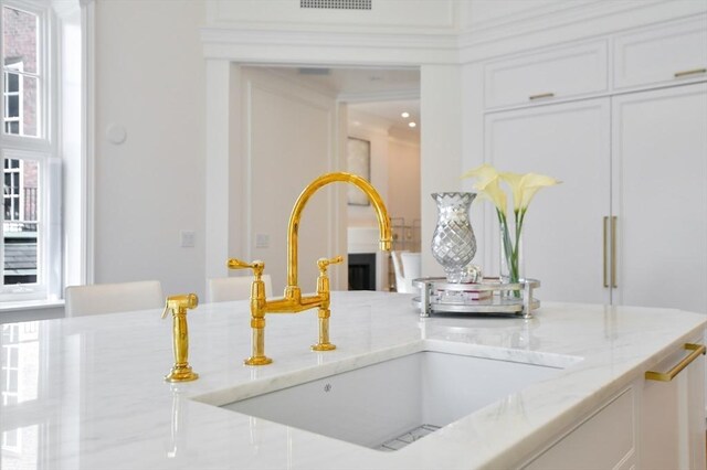 details featuring light stone counters, white cabinetry, and a sink