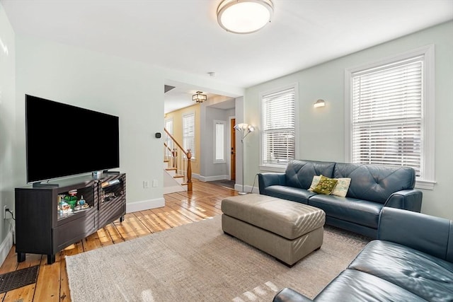 living area with light wood finished floors, plenty of natural light, and stairway