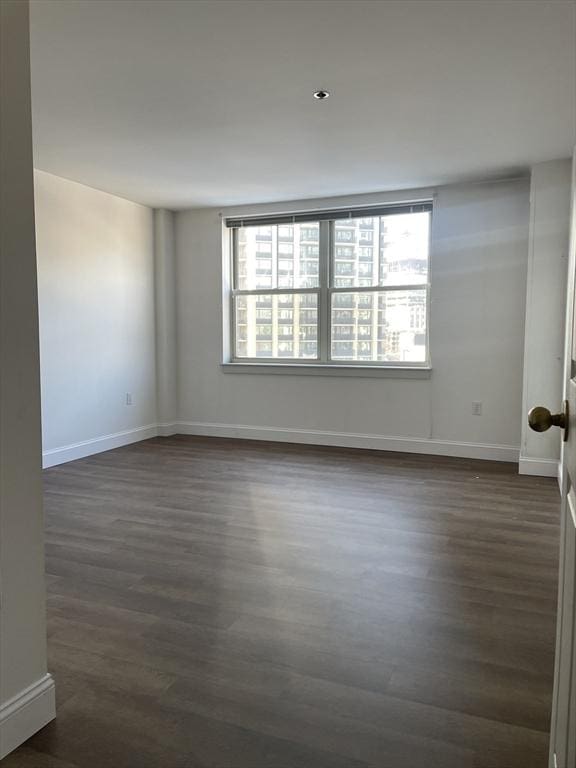 unfurnished room featuring a healthy amount of sunlight and dark hardwood / wood-style floors