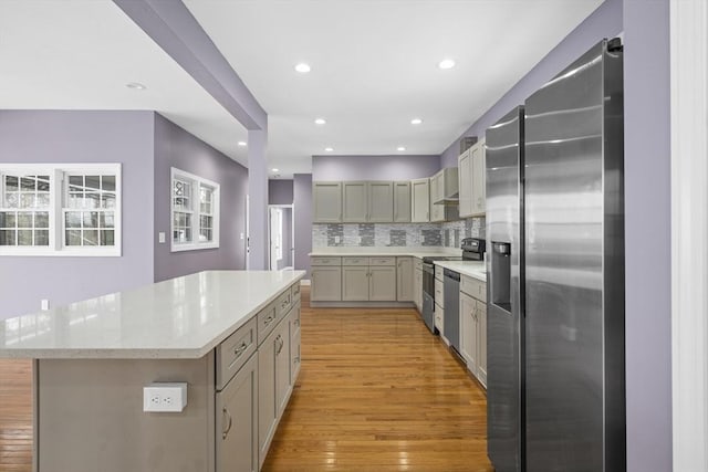 kitchen featuring a center island, light wood finished floors, recessed lighting, backsplash, and appliances with stainless steel finishes