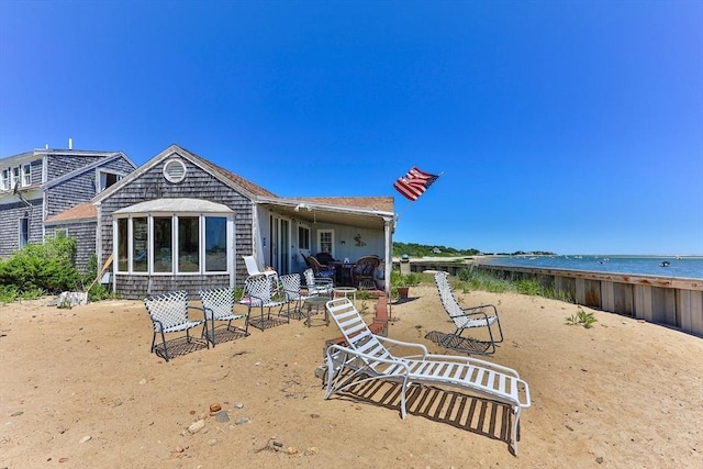 back of property featuring a view of the beach, a patio, and a water view