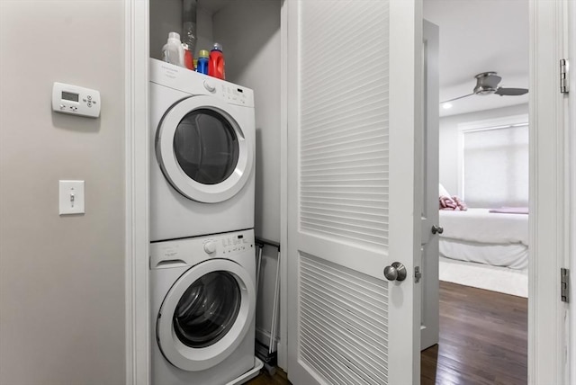 clothes washing area with estacked washer and dryer, dark wood finished floors, and a ceiling fan