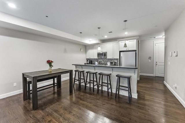 kitchen with appliances with stainless steel finishes, recessed lighting, decorative backsplash, dark countertops, and a kitchen bar