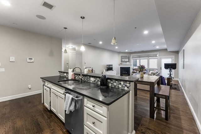 kitchen featuring a sink, dark countertops, dishwasher, baseboards, and recessed lighting