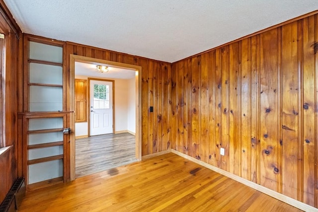 41 Yvette St, Chicopee, MA 01020 - unfurnished room with light wood-style floors, wooden walls, radiator, and a textured ceiling