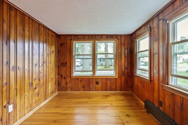 41 Yvette St, Chicopee, MA 01020 - empty room with baseboard heating, a textured ceiling, light wood finished floors, and wood walls