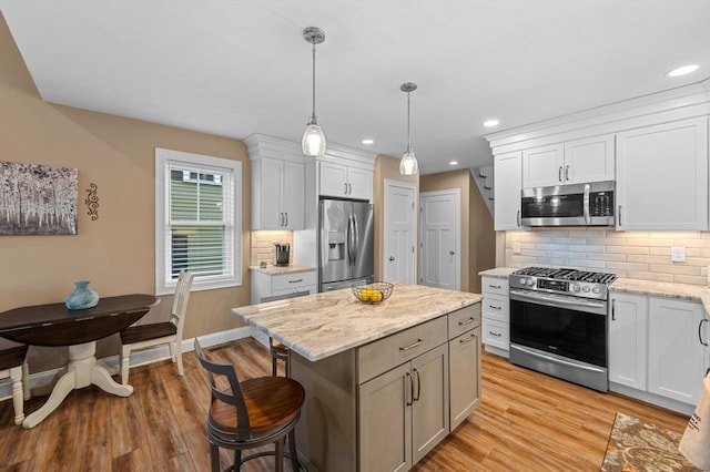 11 Soucy Dr Unit 11, Rutland, MA 01543 - kitchen with stainless steel appliances, light wood finished floors, backsplash, decorative light fixtures, and a kitchen bar