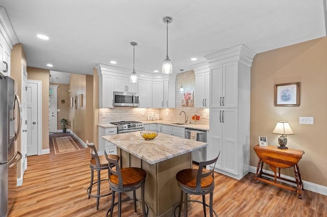 11 Soucy Dr Unit 11, Rutland, MA 01543 - kitchen with appliances with stainless steel finishes, a breakfast bar, backsplash, light wood finished floors, and pendant lighting