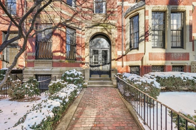 snow covered property entrance with french doors