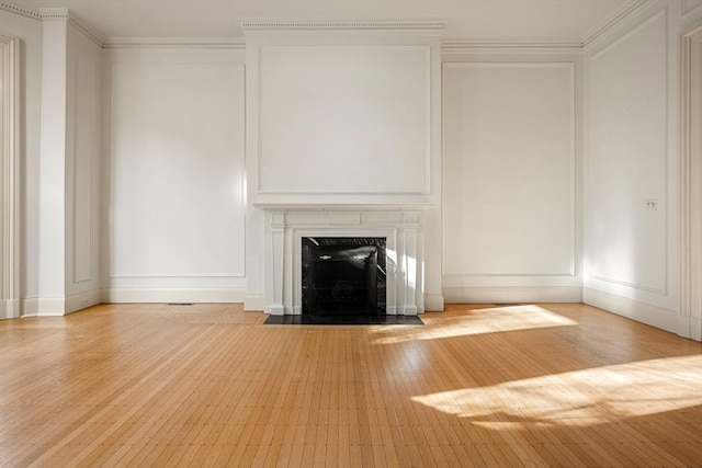 unfurnished living room with crown molding, a high end fireplace, and light hardwood / wood-style flooring