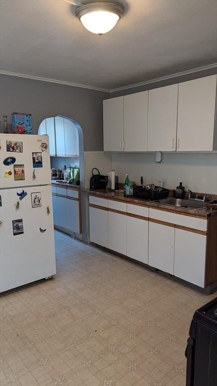 kitchen featuring white cabinets, sink, white fridge, and ornamental molding