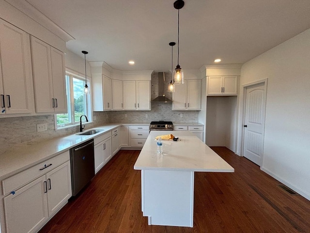 kitchen with a center island, wall chimney range hood, sink, decorative light fixtures, and stainless steel appliances