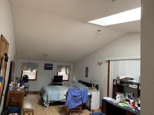 bedroom featuring light hardwood / wood-style flooring and lofted ceiling with skylight